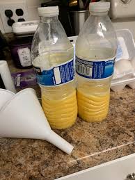 Scrambled raw eggs stored in plastic water bottles with a funnel beside them, prepared for easy transport during camping